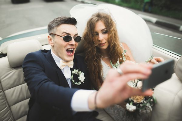 Happy groom is taking selfie with his pretty bride on wedding day.